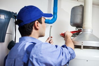 plumber with blue hat repairing old tank hot water system in wollongong